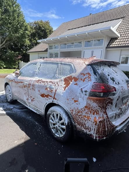 SUV covered in snow foam during an exterior wash